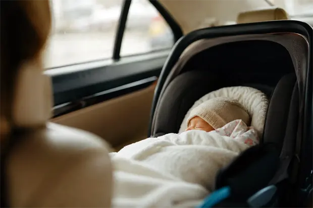 Newborn baby safely secured in a car seat during Sydney taxi transfer